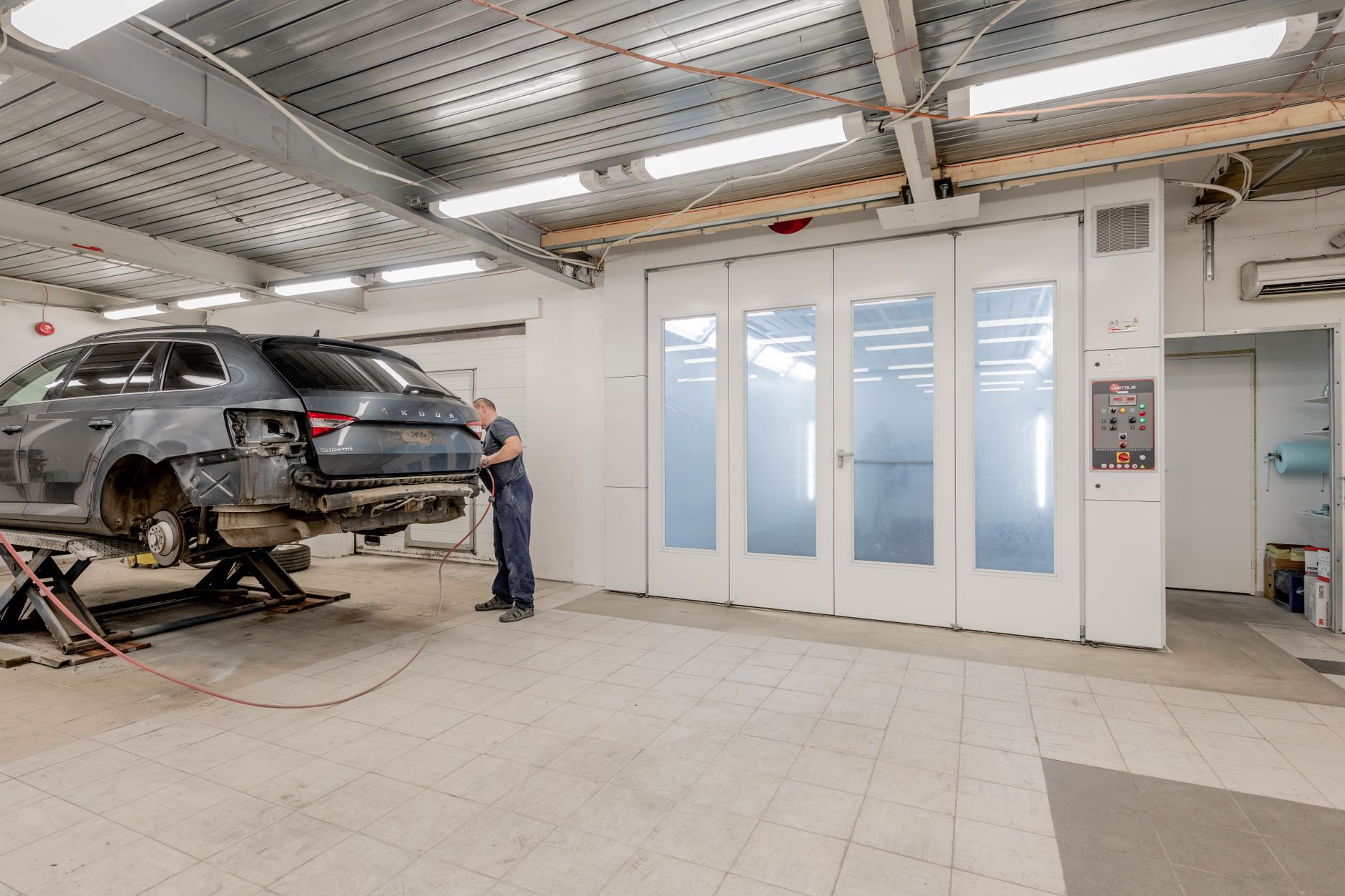 Técnico de AutoPrecisión preparando un auto en la cabina de pintura